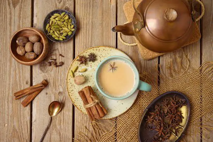 Masala chai with cinnamon, cardamom, cloves and star anise on a wooden table