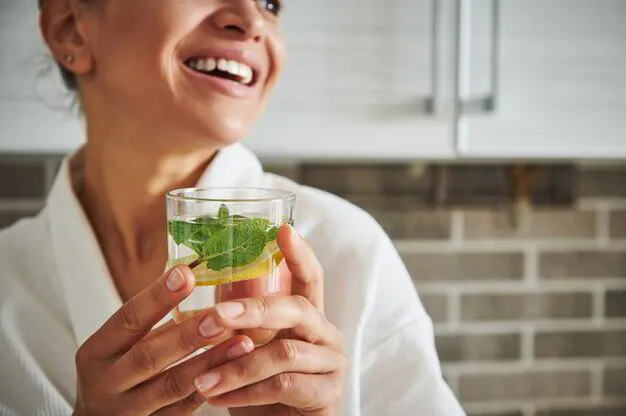 Smiling woman holding a glass of fresh mint and lemon water
