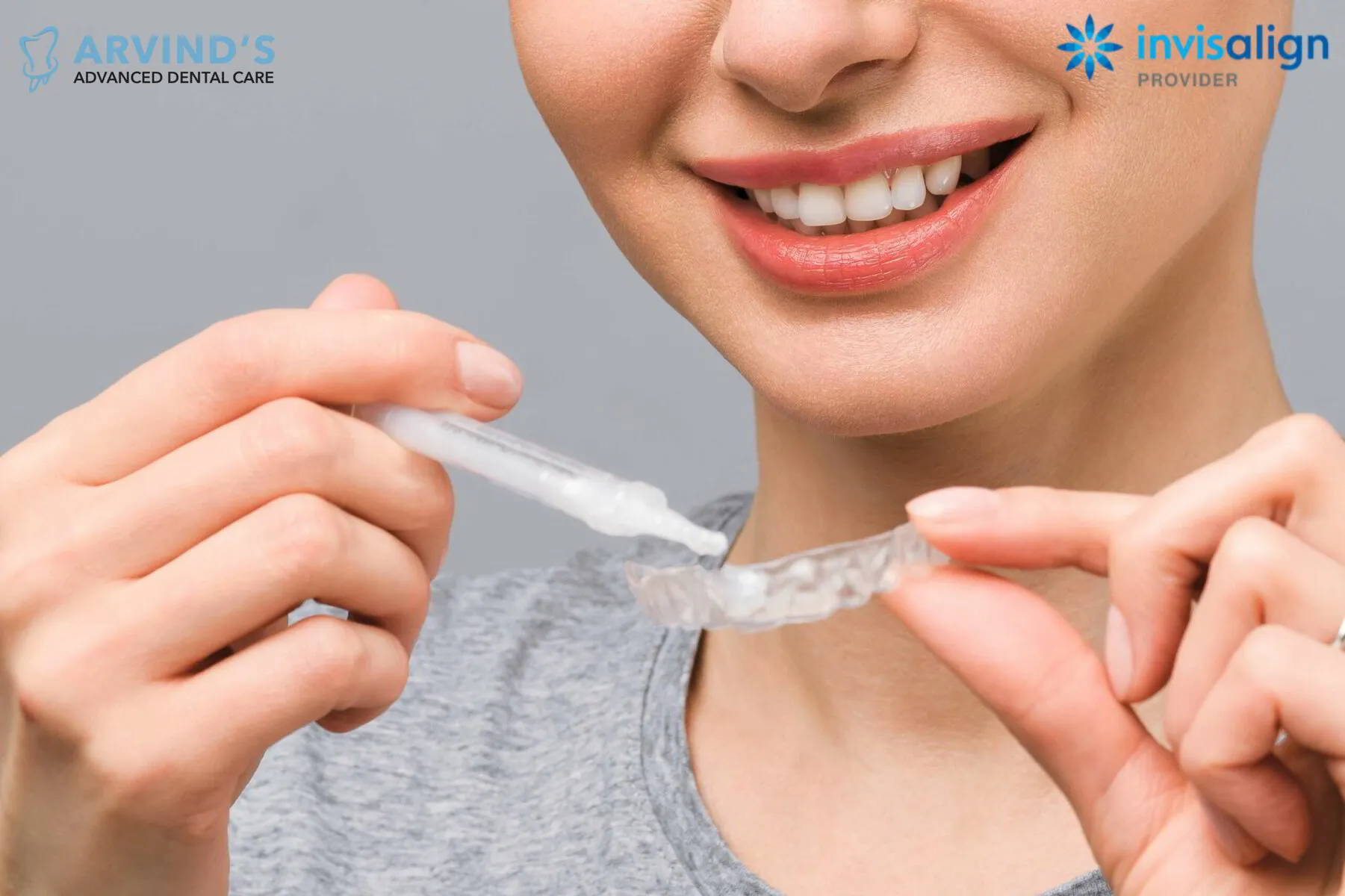 Woman holding a clear Invisalign aligner and cleaning it with a toothbrush