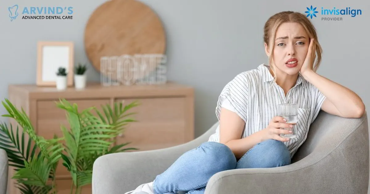 Woman experiencing tooth pain and holding her cheek while sitting at home