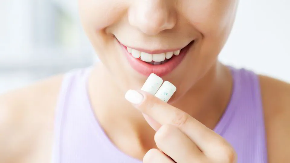 Woman smiling while holding a dental chewing gum or oral care product