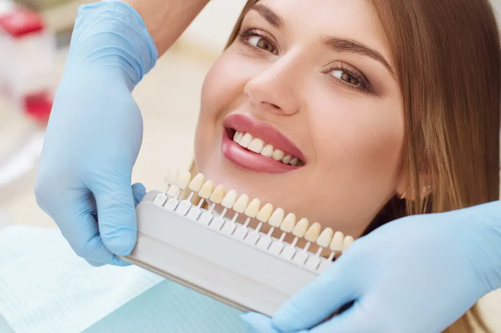 Dentist using a shade guide to check a patient's tooth color
