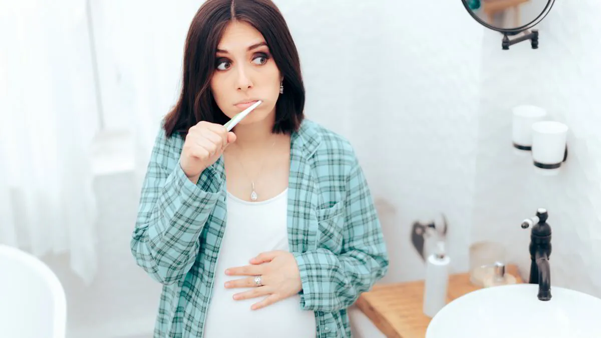 Pregnant woman brushing her teeth as part of daily oral hygiene